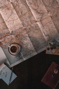 Flat lay of map, coffee, coins, and notebook for travel planning.